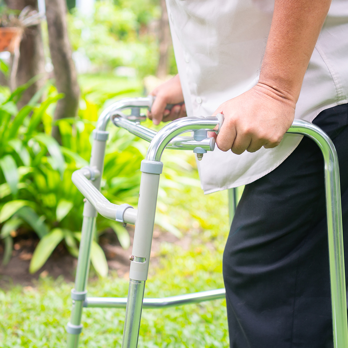 Happy old elderly Asian man uses a walker and walks in the backy
